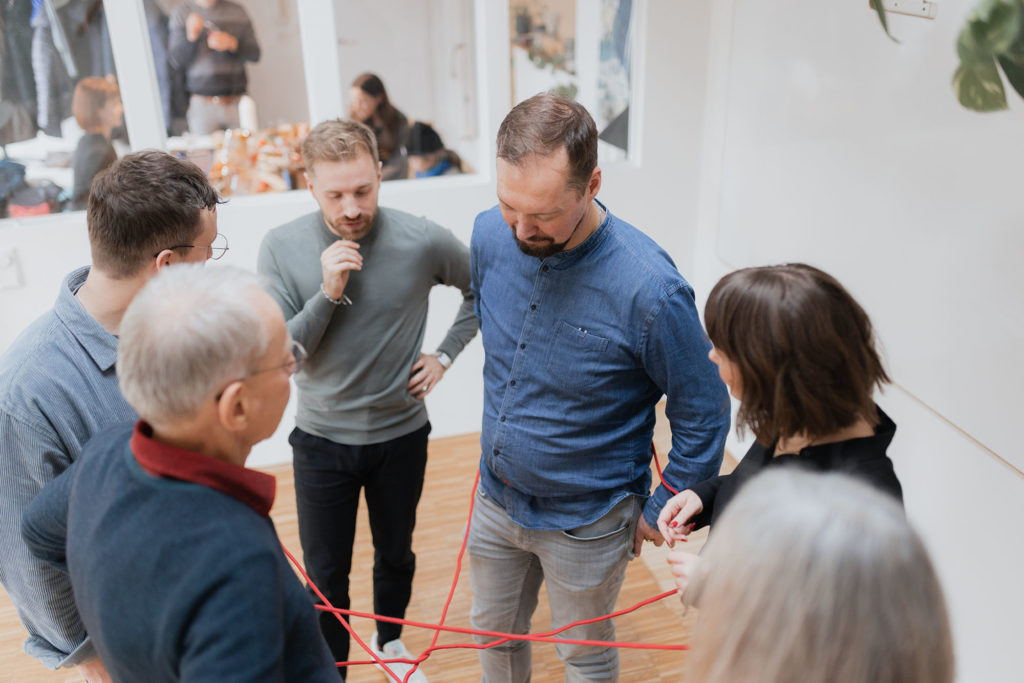 Selbstorganisiertes Team löst gemeinsam ein Problem im Workshop anhand eines exemplarischen roten Fadens